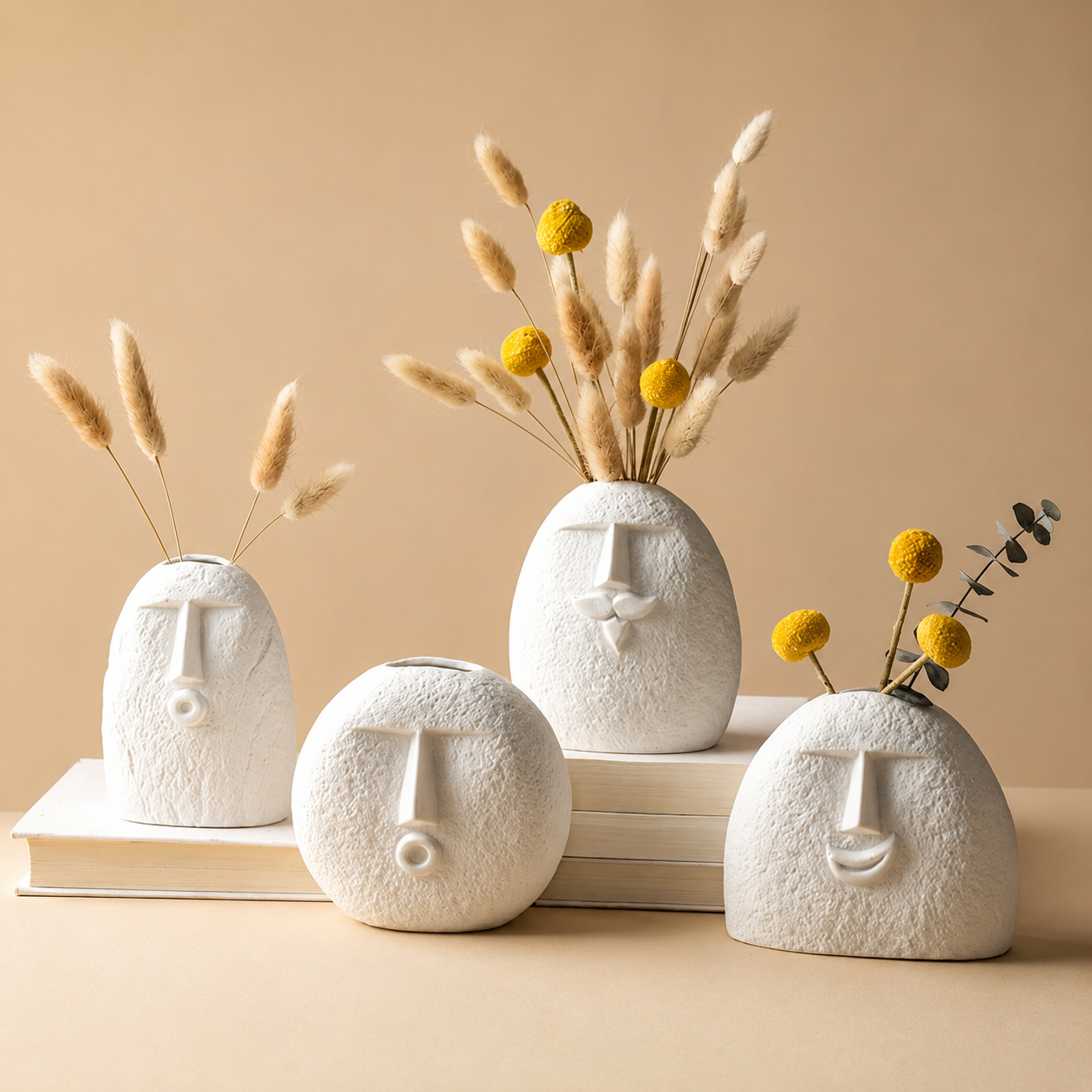Set of four abstract face vases with dried flowers on beige background