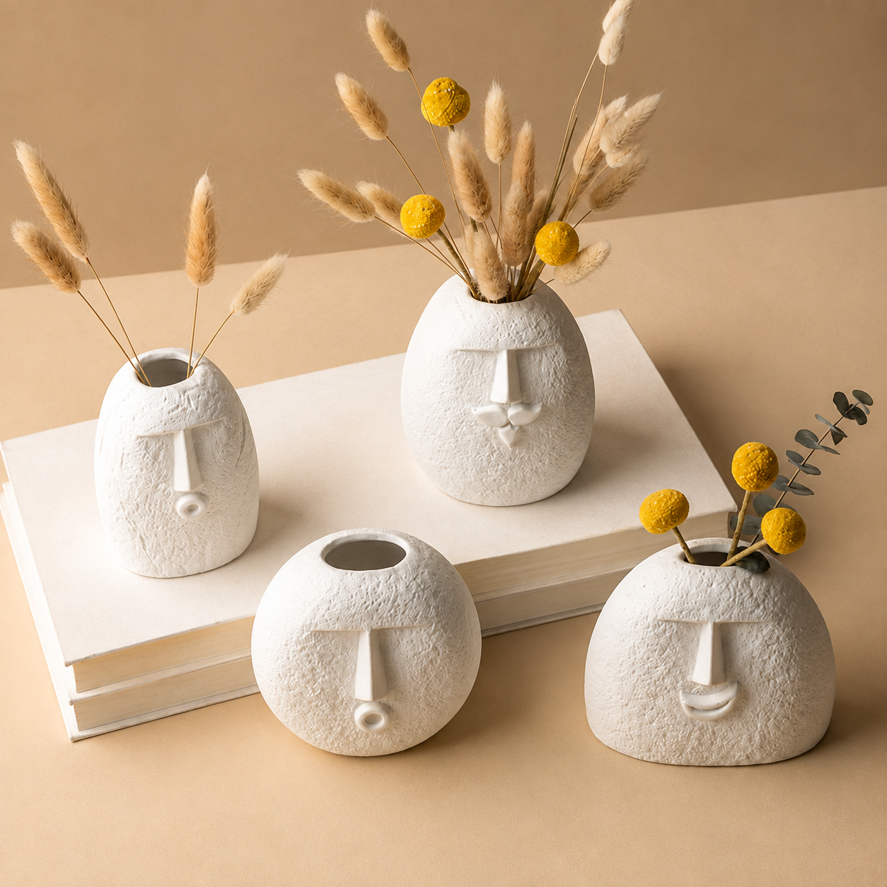 Four abstract face vases displayed on books