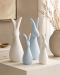 Set of four abstract rabbit sculptures in white and blue on beige shelf