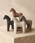 Set of four abstract horse sculptures in earthy tones on stone pedestal