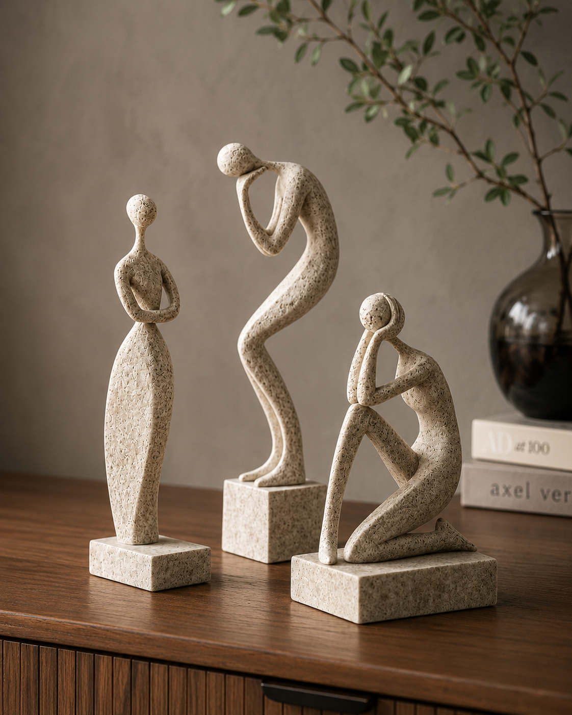 Three abstract figure sculptures on wooden dresser with dark vase