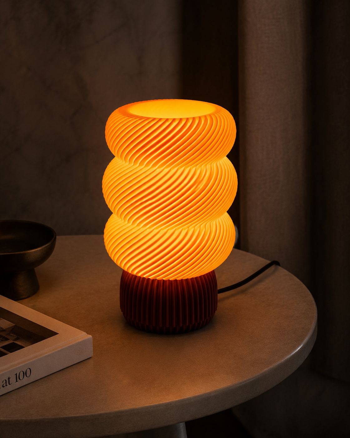 Sculptural spiral lamp on round side table with dark curtain background