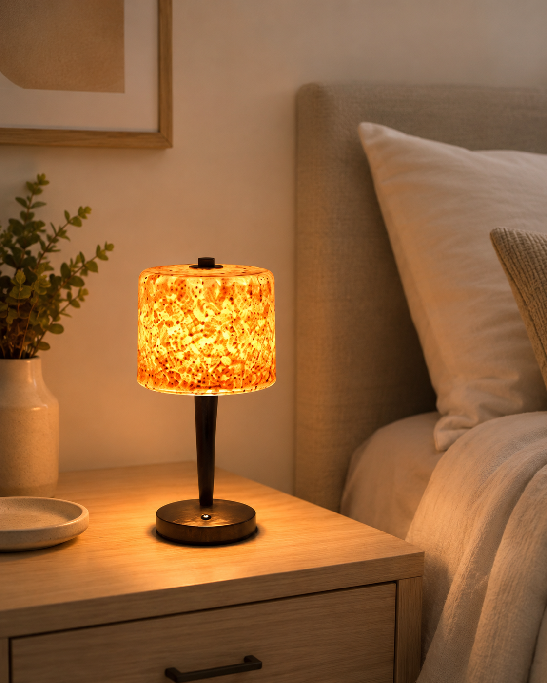 Amber terrazzo glass table lamp glowing warm on oak bedside table